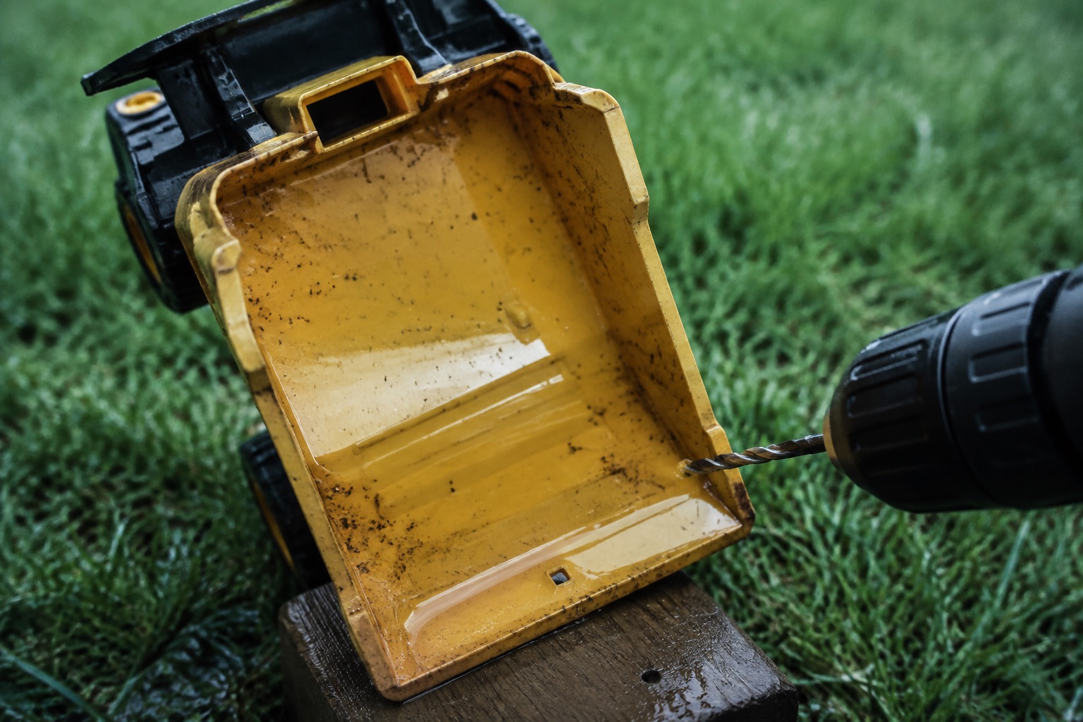 Toy dump truck holding rainwater, drill making drain hole in lowest corner